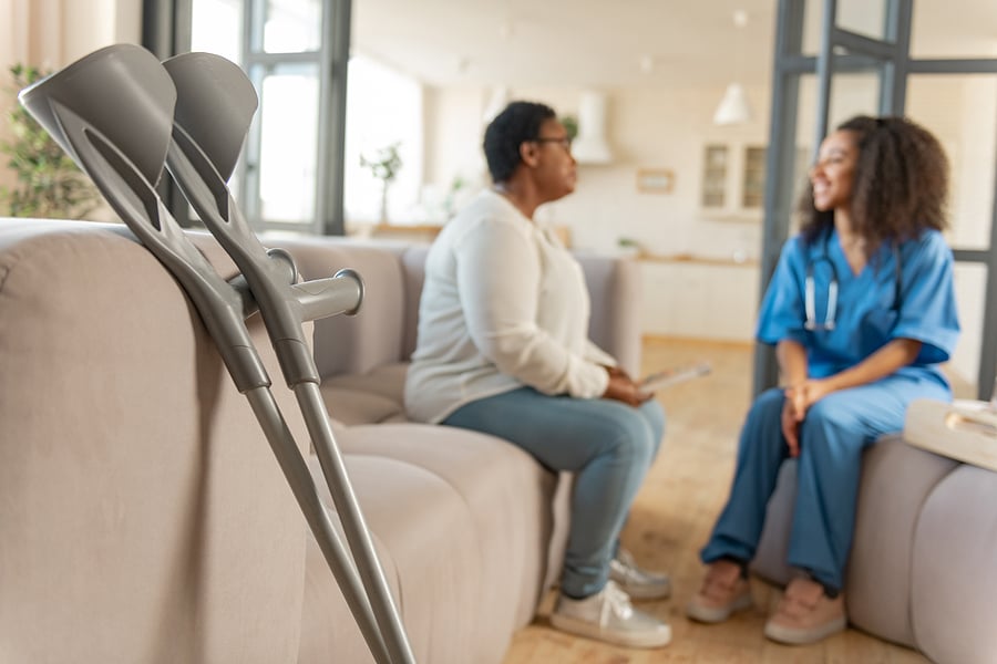 Occupational health nurse practitioner talking to patient on crutches