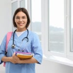 MSN nursing student in college classroom with backpack and books.