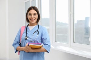 MSN nursing student in college classroom with backpack and books.