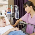 Acute care nurse practitioner caring for female patient in a hospital bed.