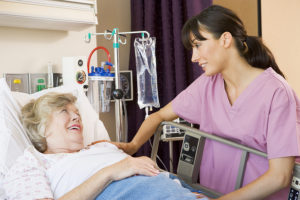 Acute care nurse practitioner caring for female patient in a hospital bed.