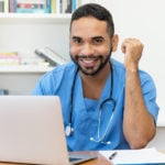 Male nursing student at laptop completing an online MSN degree.
