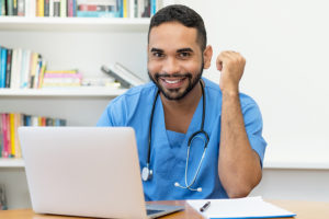 Male nursing student at laptop completing an online MSN degree.