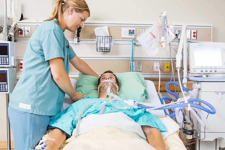 Critical Care Nurse Practitioner tending to a patient in a hospital bed