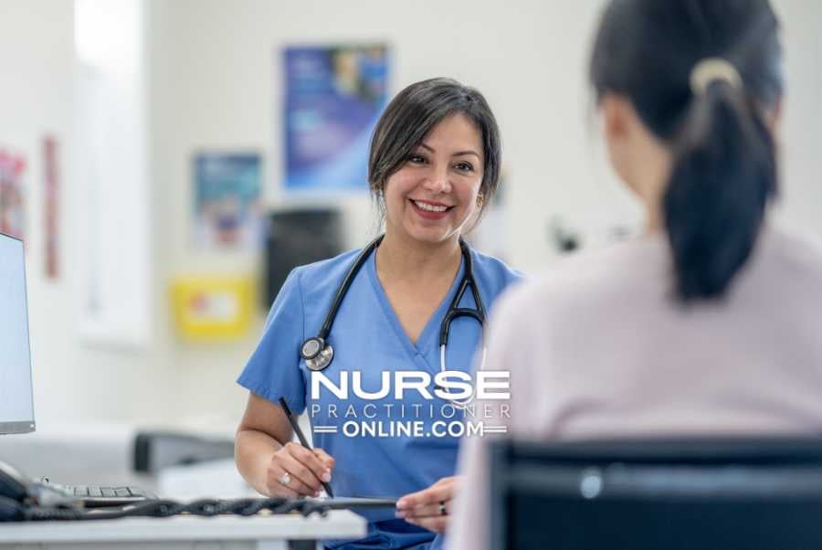 A nurse practitioner checks in with a colleague at a desk in a hospital.