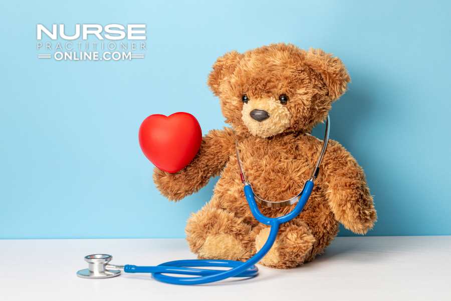 A stuffed bear holds a heart while wearing a stethoscope around its neck.
